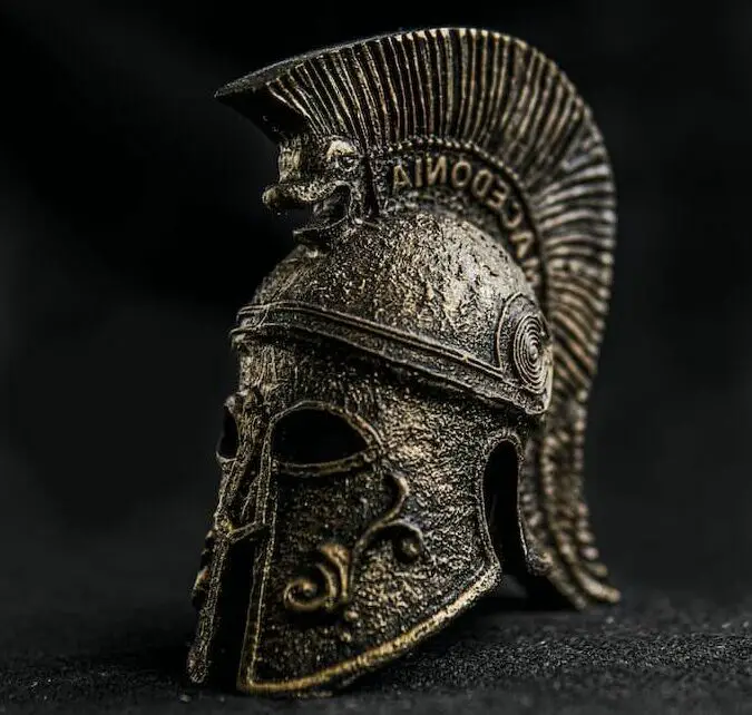 Antiker griechischer Helm aus Bronze mit dekorativen Elementen im Museum in der Dunkelheit